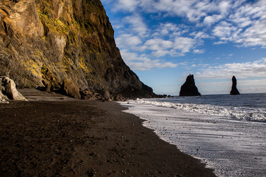Image of black sand beach near Vik at South Coast of Iceland. White foam on a black lava beach in southern Iceland. Attractions and nature of Iceland.