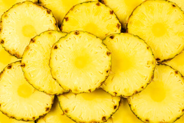 Pineapple juicy yellow slices background. Top view.