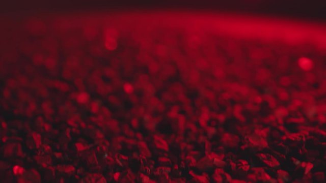 Small sand particles moving through vibrations of sound. Macro shot with red neon light.
