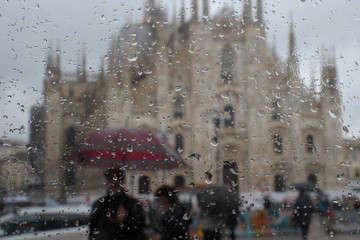 Milano e il duomo in una giornata di pioggia, gocce d'acqua e persone con ombrello visitano la citta'