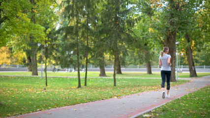 Girl athlete jogging in the park. Workout. Healthy lifestyle.