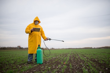 Farmer in yellow coat, controls the work in the field over its tablet.