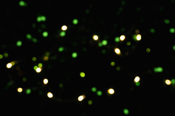 Fototapeta na wymiar Bokeh of yellow and green lights. Sequins on dark background