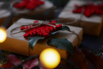 New Year and Christmas gifts packed in natural paper with red decoration and green branch on a dark background with yellow bokeh light. Calendar, presents, advent and Christmas card concept.