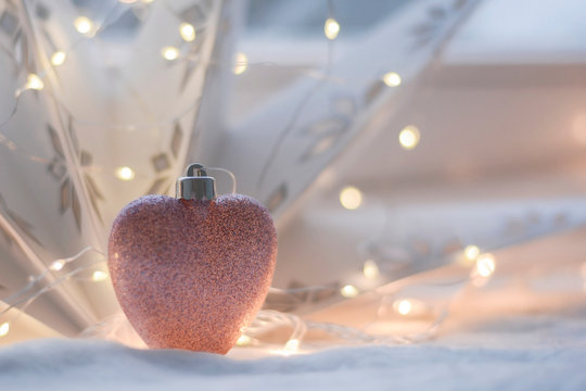 Winter Wonderland Indoor Decoration Made Of Ornament Pastel Pink Heart With Glitter And New Year’s Bokeh Light. Calendar, Advent And Christmas Card Concept.