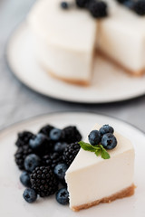 cheesecake New York with fresh berries and a slice on a plate