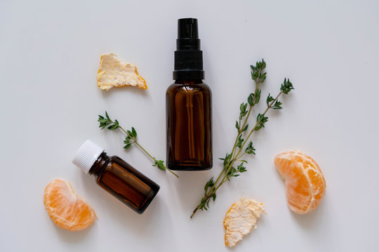 Natural pharmacy flat lay photo with glass bottles, fresh herbs and citrus fruit peel and chunks.