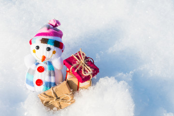 toy snowman with gifts in the snow