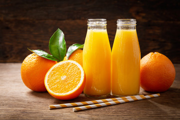 Obraz na płótnie Canvas bottles of fresh orange juice with fresh fruits