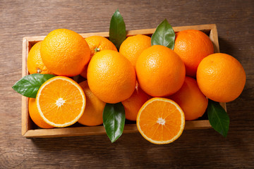 fresh orange fruits with leaves in a wooden box