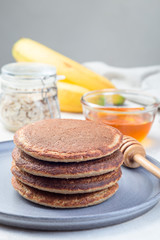 Stack of healthy oatmeal banana pancakes on  gray plate, vertical