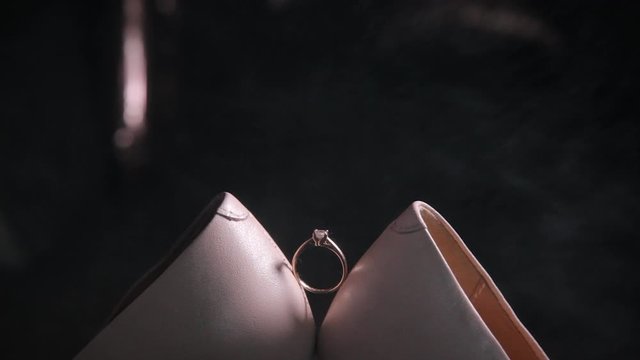 The ring between the bride's wedding shoes in the dark. Wedding day