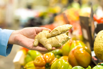 Female hand choosing ginger in supermarket. Concept of healthy food, bio, vegetarian, diet.