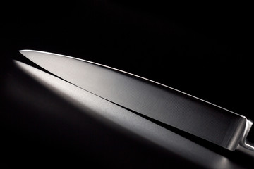 Kitchen knife with a white handle on a black background. A sharp blade of a knife.