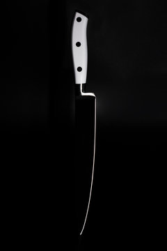 Kitchen knife with a white handle on a black background. A sharp blade of a knife.