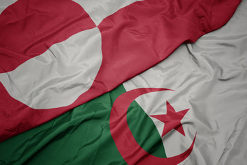 waving colorful flag of algeria and national flag of greenland.