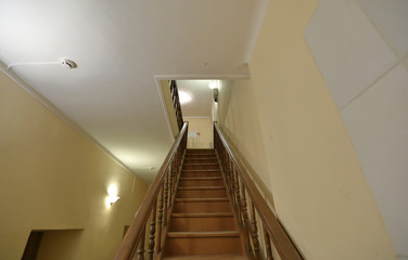 Old brown wood staircase with a handrail in a building without an elevator