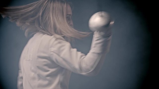 Fencing training - young woman fencer with long hair showing basics of fencing attacks