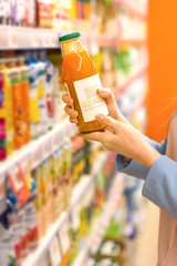 Woman hand choosing a juice at supermarket. Concept of healthy food, bio, vegetarian, diet.