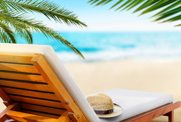 Beach lounger with straw hat on the beach. Travel vacation concept.