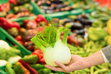 Female hand choosing fennel in supermarket. Concept of healthy food, bio, vegetarian, diet.