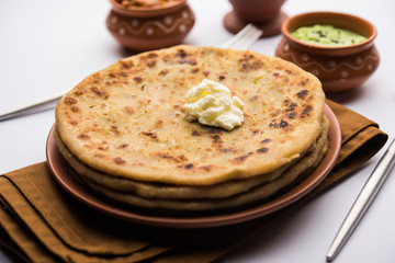 Aloo Paratha / Indian Potato stuffed Flatbread with butter on top. Served with fresh sweet Lassi, chutney and pickle . selective focus