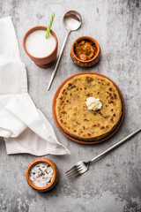 Aloo Paratha / Indian Potato stuffed Flatbread with butter on top. Served with fresh sweet Lassi, chutney and pickle . selective focus