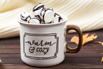 Hot cocoa with marshmallow in a ceramic mug on a wooden table. Concept of home comfort. 