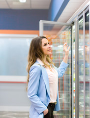 Woman choosing a dairy products at supermarket. Reading product information