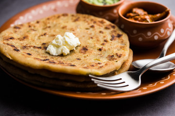 Aloo Paratha / Indian Potato stuffed Flatbread with butter on top. Served with fresh sweet Lassi, chutney and pickle . selective focus