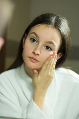 Portrait of a beautiful girl with skin problems in the mirror