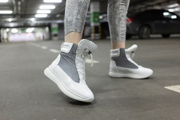 Fototapeta na wymiar sneakers leather white gray demi season. On foot, a model in an underground parking lot. Close up