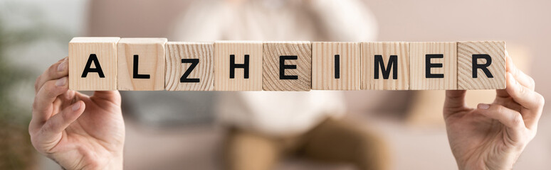 panoramic shot of senior woman holding wooden cubes with alzheimer letters
