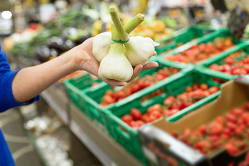 Female hand choosing fresh garlic in supermarket. Concept of healthy food, bio, vegetarian, diet.