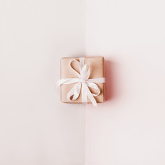 Gift box with white bow on pastel geometric background. Monochrome beige colors. Zero Waste Holiday concept