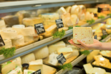 Woman's hand choosing cheese in supermarket. Concept of healthy food, bio, vegetarian, diet.