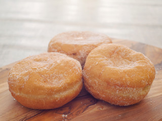 Three fresh jam doughnut on a wooden board, Pastry product.
