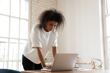 Puzzled young african american employee writing email response.