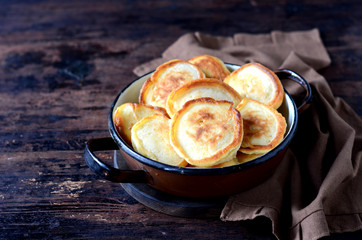 overhead breakfast shot with tasty fried russian pancakes in a bowl on a dark wooden table