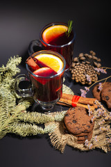 Christmas composition with mulled wine, oranges, chocolate cookies and branches of spruce on a dark black background. Winter drink. Hot Christmas Mulled Wine. 