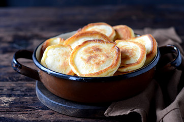 overhead breakfast shot with tasty fried russian pancakes in a bowl on a dark wooden table