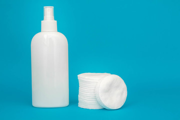 Cotton pads and plastic bottle on blue background. Spa concept. Cotton Cosmetic Makeup Removers Tampons. Copy, empty space for text
