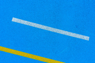 Fototapeta na wymiar Colorful sports court background. Top view blue field rubber ground with white and yellow lines outdoors