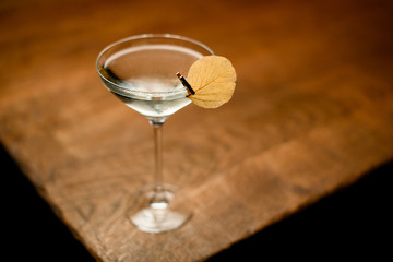 Alcoholic cocktail in the glass decorated with a dried leaf on the pin