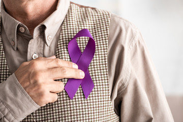 cropped view of retired man holding purple ribbon