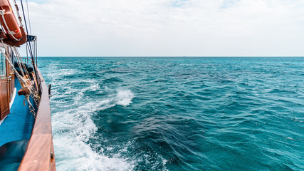 The stern of a ship with the trail in the sea in the background