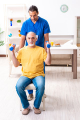 Fototapeta na wymiar Young male doctor visiting old patient at home