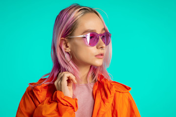 Millennial enigmatic pretty girl with unusual pink dyed hairstyle. Golden sequins as tears, nose piercing. Mysterious hipster teenager on blue background.