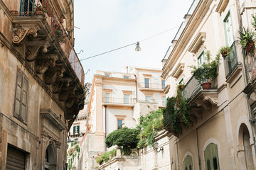 low angle view of plants on balconies of old houses in modica, Italy