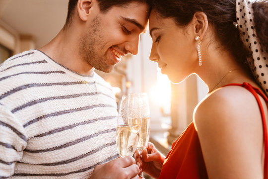 Image of happy couple standing head to head and drinking champagne